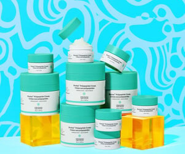 photo of multiple Protini full size and littles contatiners stacked on top of each other, one open showing teh cream, some sitting on acryclic boxes, all agains ad image